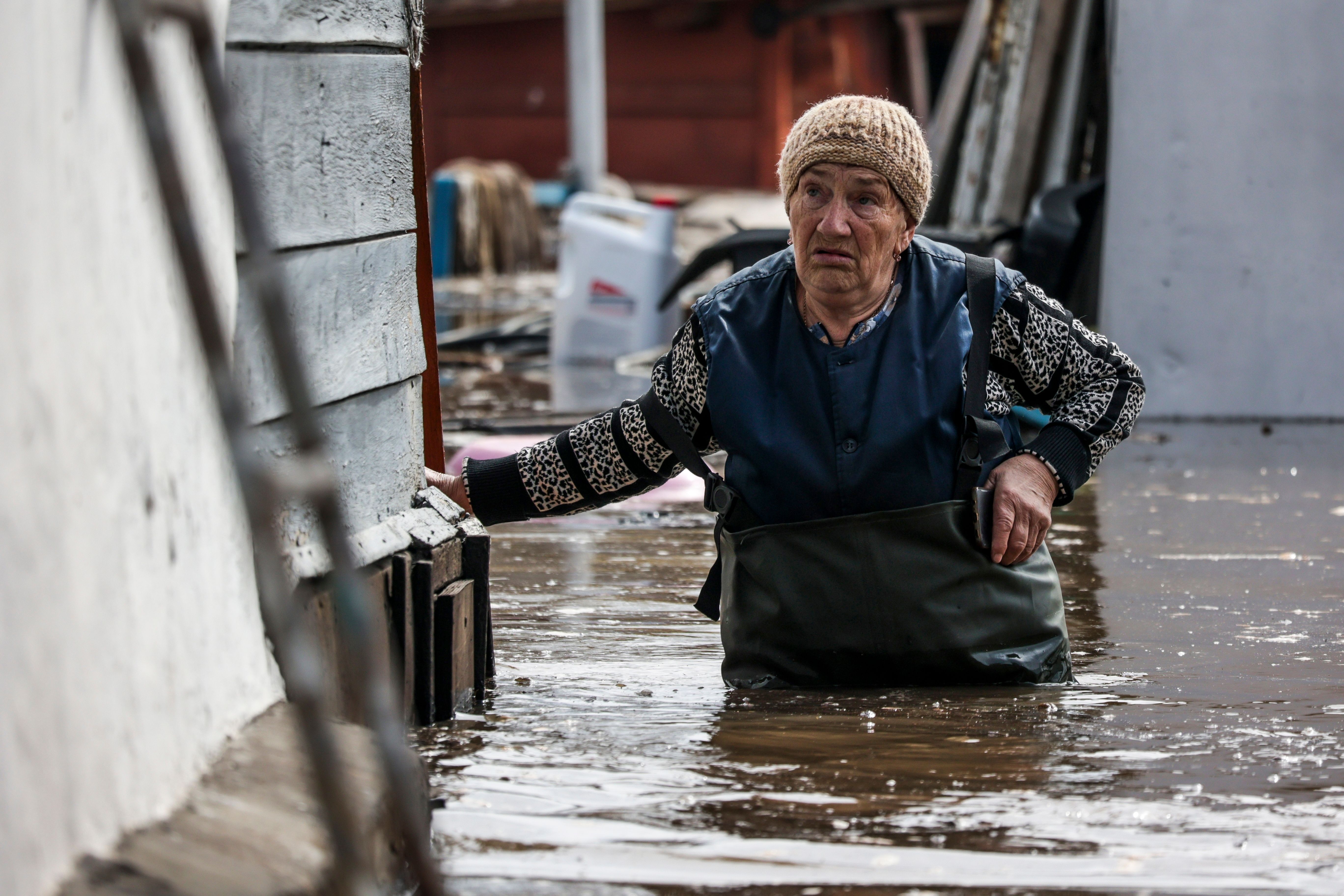 Eine Frau watet durch das Wasser in der Nähe ihres Hauses in einem überschwemmten Gebiet in Orenburg.