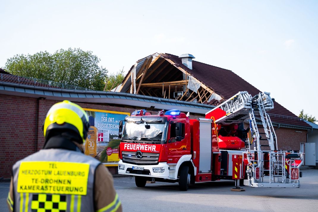 30. Juli 2024, Ratzeburg: Einsatzkräfte der Feuerwehr sind bei einem teilweise eingestürzten Dach eines Supermarktes im Einsatz.