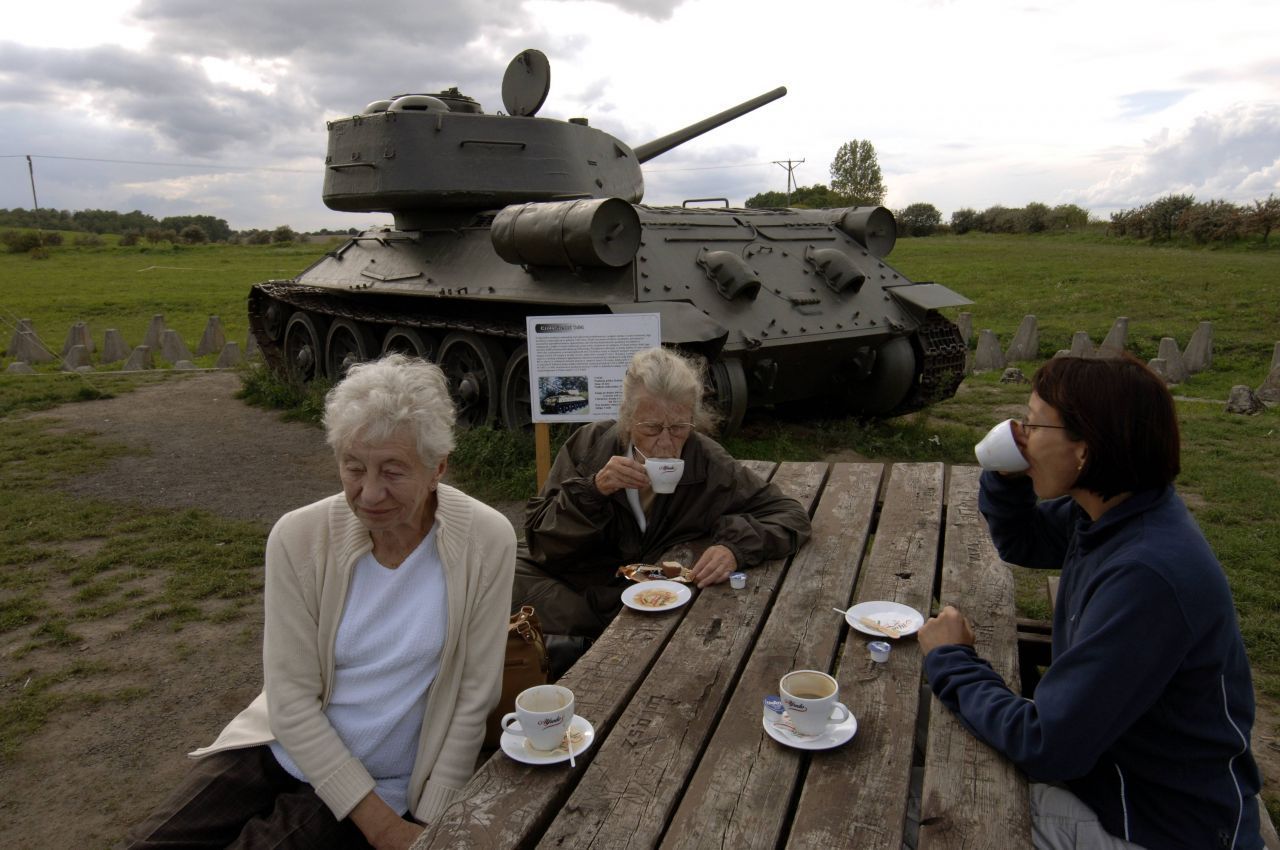 Besucher:innen während einer Kaffeepause neben einem Panzer nahe des Militärmuseums.