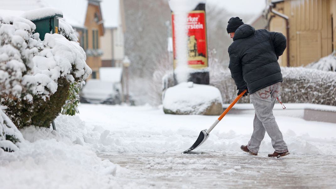 Archiv: Mit einem Schneeschieber räumt ein Anwohner in Schierke den Schnee vom Gehweg. 