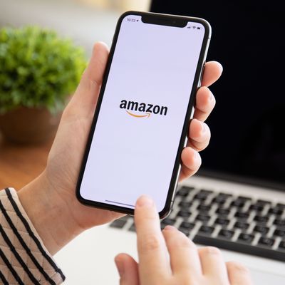 Woman holding iPhone X with Internet shopping service Amazon