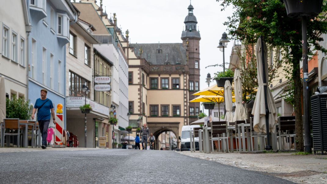 Fußgänger laufen über die Rückertstraße. In Hintergrund ist das Rathaus zu sehen. 