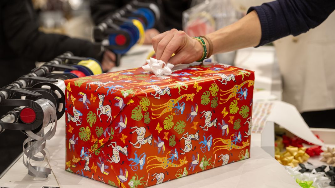 In einem Kaufhaus verpackt eine Verkäuferin für Kunden ein Weihnachtsgeschenk. (z