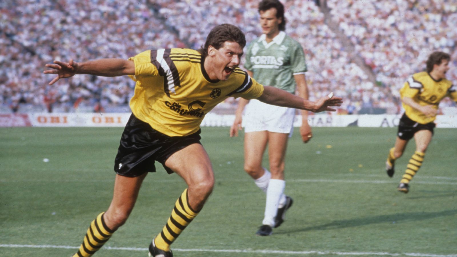 
                <strong>24. Juni 1989: Finale in Berlin </strong><br>
                BVB-Ikone Norbert "Nobbi" Dickel machte sich im Endspiel des DFB-Pokals unsterblich. Beim 4:1-Sieg im Finale wurde Dortmunds Kult-Stadionsprecher zum großen Faktor für die Borussia und schoss die Westfalen mit zwei Treffern zum zweiten Pokalsieg nach 1965. Für den BVB endete damit eine 23-jährige Durststrecke ohne Titel nach dem Gewinn des Europapokals der Pokalsieger 1966. Dickel musste seine Karriere wenig später aus Verletzungsgründen beenden. Auf die Titelmelodie der Serie "Flipper" huldigen die BVB-Fans ihren Pokalhelden bis heute: "Wir singen Norbert, Norbert, Norbert Dickel, jeder kennt ihn, den Held von Berlin!"
              