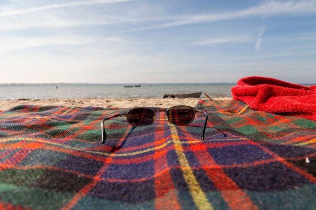 Eine Sonnenbrille mit UV-Schutz schützt, sobald es an den Strand geht.