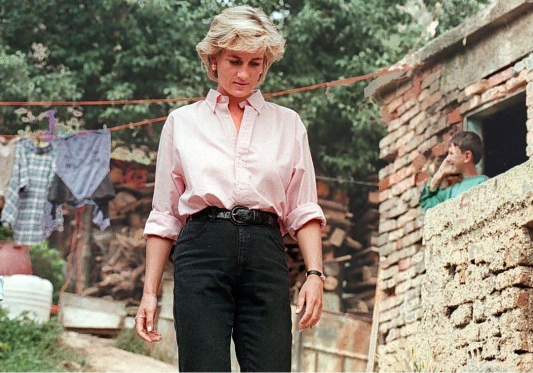 Diana trägt klassische schwarze Jeans zu einer Bluse. Dieses Outfit geht auch 2022.
