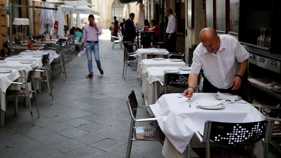 Ein Kellner deckt in Sevilla Tische. Wer wo sitzt und was das kostet, ist in der spanischen Stadt Gegenstand einer Diskussion.