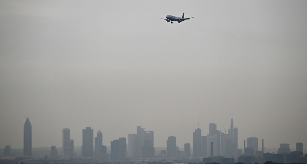 Ein Airbus A321-200 der Lufthansa ist im Landeanflug auf die Nordwest-Landebahn des Flughafens, während die Hochhäuser der Bankenstadt Frankfurt im Dunst liegen.