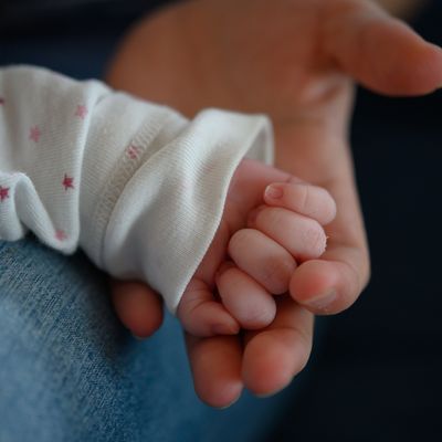 Symbolbild: Die Hand eines zwei Wochen altes Neugeborenen liegt in der Hand seiner Mutter.