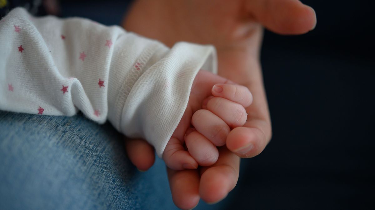 Symbolbild: Die Hand eines zwei Wochen altes Neugeborenen liegt in der Hand seiner Mutter.