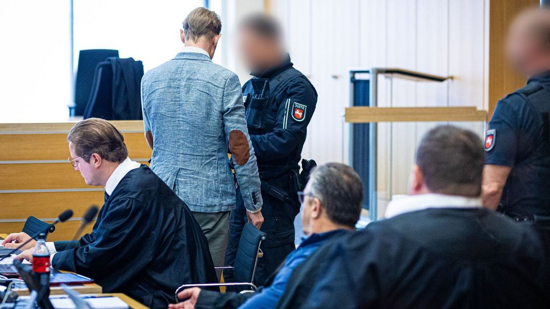 Ein Justizmitarbeiter (oben r) löst bei dem Angeklagten Christian B. (oben l) in einen Gerichtssaal im Landgericht die Handfesseln.