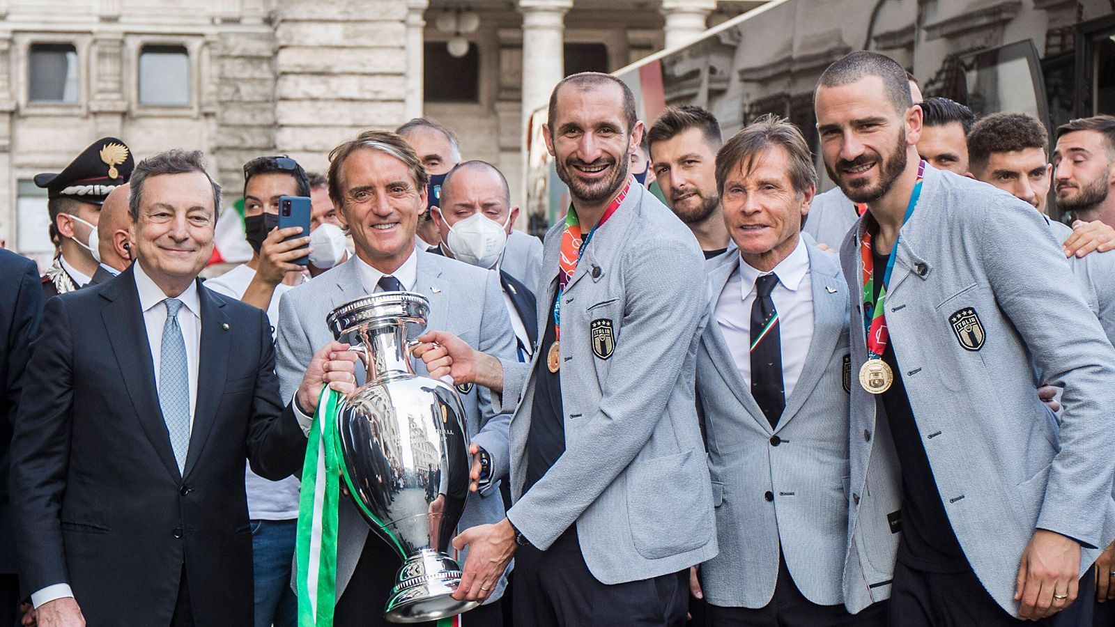 
                <strong>Gruppenfoto mit Draghi</strong><br>
                Trainer Mancini hält den Pokal, Ministerpräsident Draghi steht ganz links. Auch Leonardo Bonucci (r.), der das 1:1 erzielte und im Elfmeterschießen getroffen hatte, stellt sich zum Erinnerungsfoto.
              