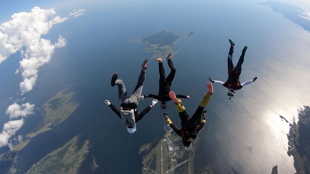 Fallschirmspringer fallen im Luftflug durch klaren Himmel.