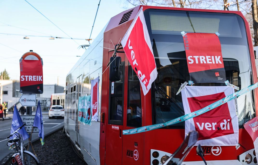 Eine mit Streik-Plakaten beklebte Straßenbahn der Kölner Verkehrs-Betriebe (KVB) steht vor dem Bahndepot. (Symbolbild)