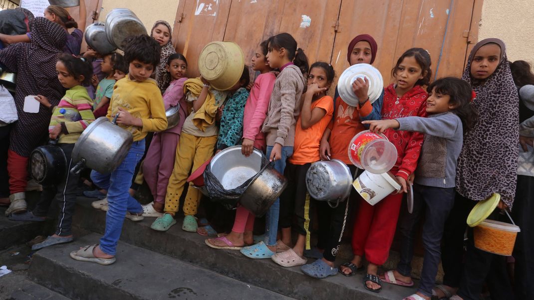 Kinder warten in Schlangen an Essensausgaben im Gazastreifen.