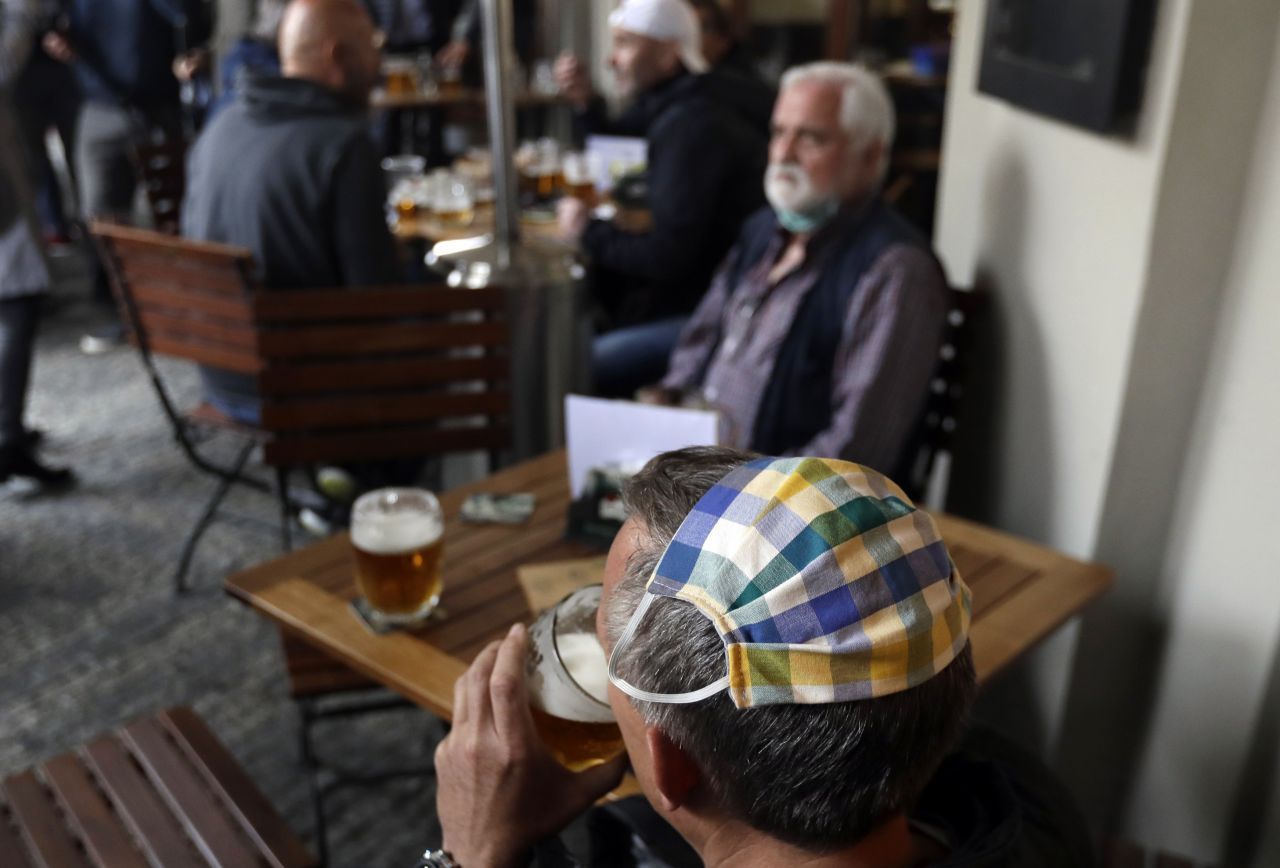 Tschechien, Prag: Ein Mann, der seinen Mundschutz auf dem Hinterkopf trägt, trinkt ein Bier in dem Außenbereich eines Restaurants. Bars, Restaurants und Cafés mit Sitzplätzen im Freien haben nach 2 Monaten wieder geöffnet - die Innenräume der Lokale bleiben aber weiterhin geschlossen.