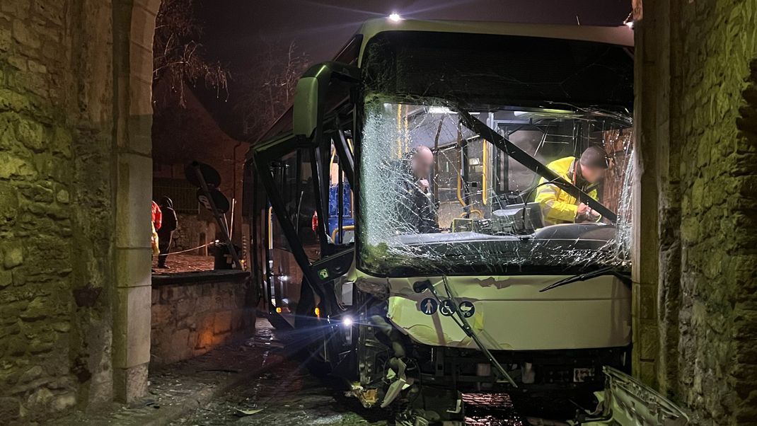 Am Mittwochmorgen steht in Sommerhausen im Landkreis Würzburg ein schwer beschädigter Bus in einem Torbogen.