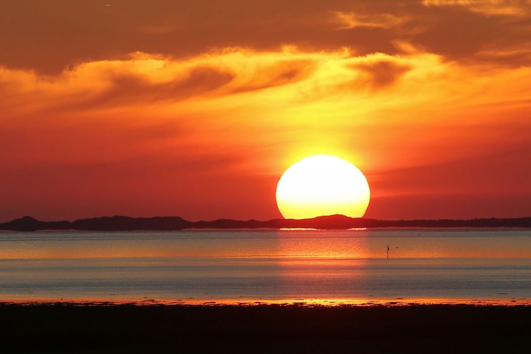 Bei einem Sonnenuntergang wie hier in Schleswig-Holstein sehen wir vor allem die rote Strahlung des Sonnenlichts. Der blaue Anteil ist auf dem abendlichen Weg durch die Atmosphäre herausgefiltert worden.