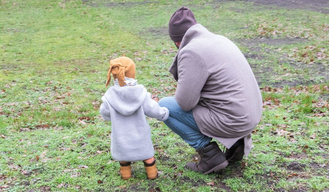 Ein Vater spielt mit seinem Sohn in einem Park.