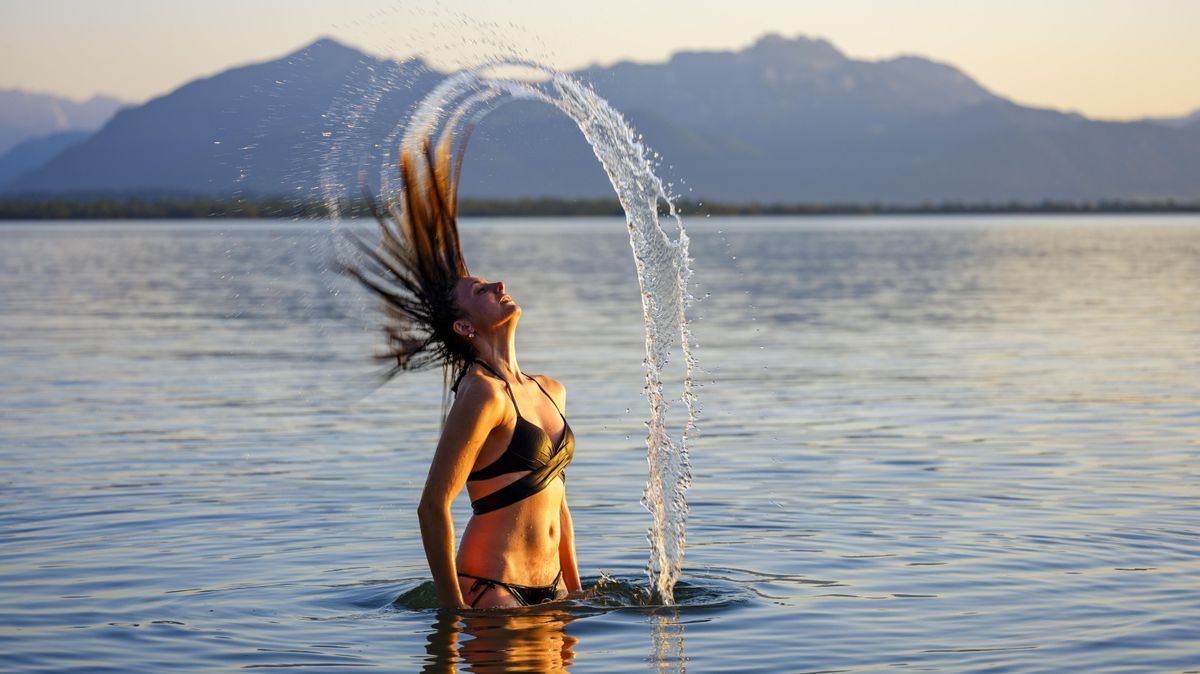 Junge Frau im Wasser wirft ihre langen Haare mit einem Wasserschwall zurück, Chiemsee 428476066