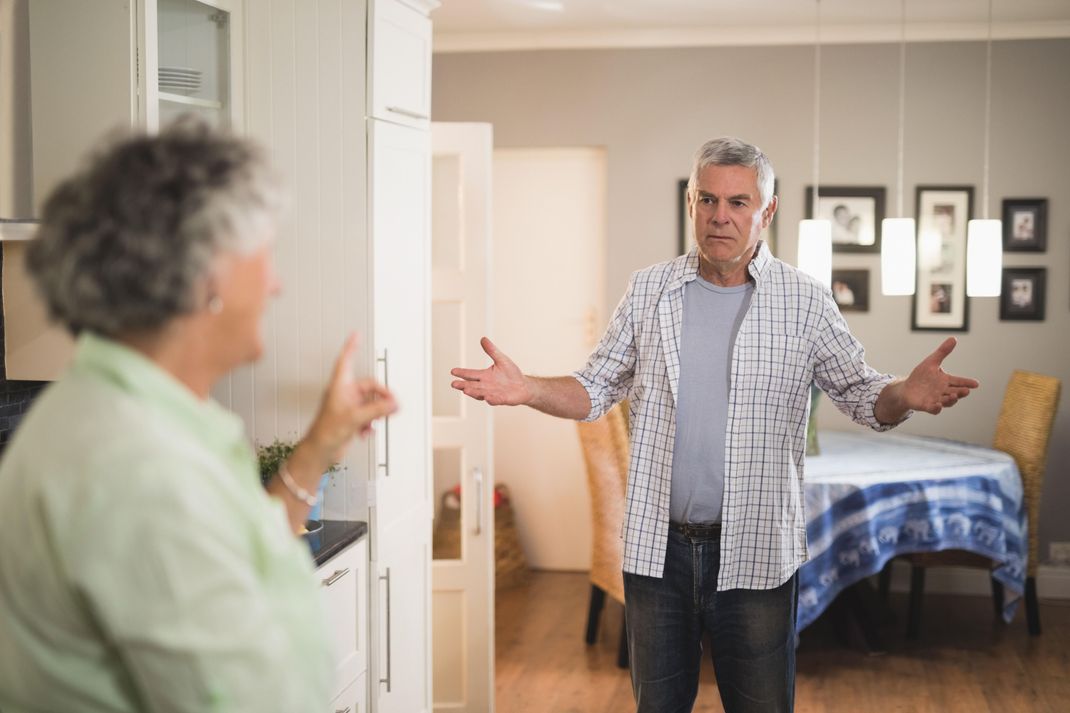 Angry senior man looking at female partner in living room || Modellfreigabe vorhanden