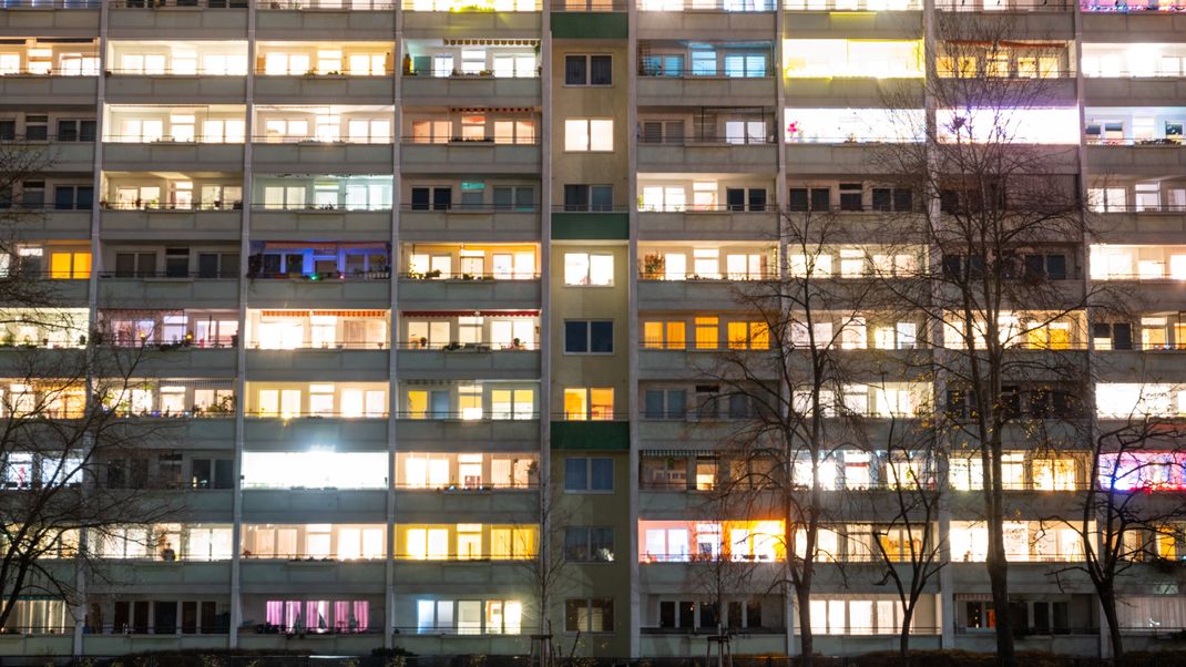 In einem Hochhaus in Berlin-Lichtenberg sind einige Fenster beleuchtet.