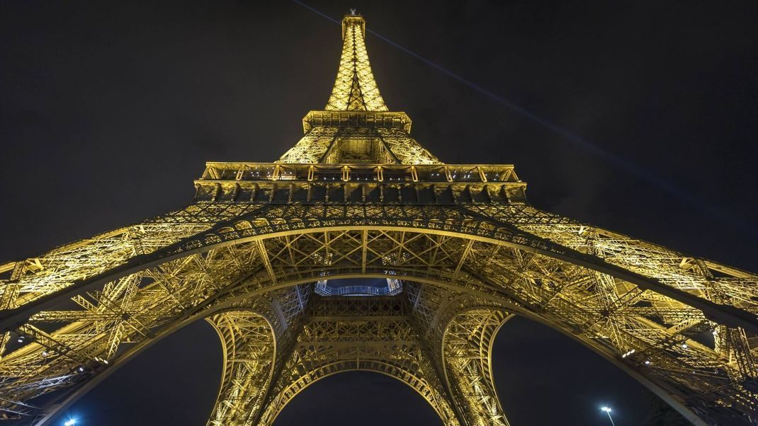 Der Eiffelturm bei Nacht angeleuchtet: Ein Foto, das du nicht machen darfst. Aber kleiner Tipp: Als Teil der Stadt-Skyline ist es erlaubt. Und mit dem Hinweis "Copyright Tour Eiffel/Illuminations Pierre Bideau" auch für Tourist:innen kostenlos erlaubt.