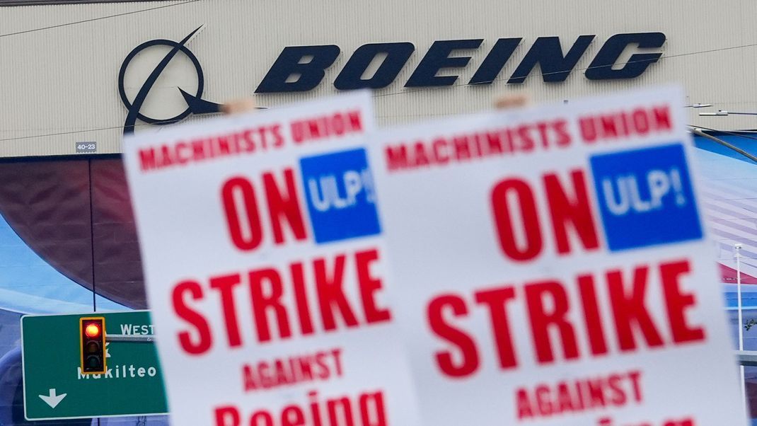 Boeing-Beschäftigte schwenken vor dem Werk Streikpostenschilder. Beim kriselnden Flugzeugbauer Boeing ist die größte Gewerkschaft in den Streik getreten.