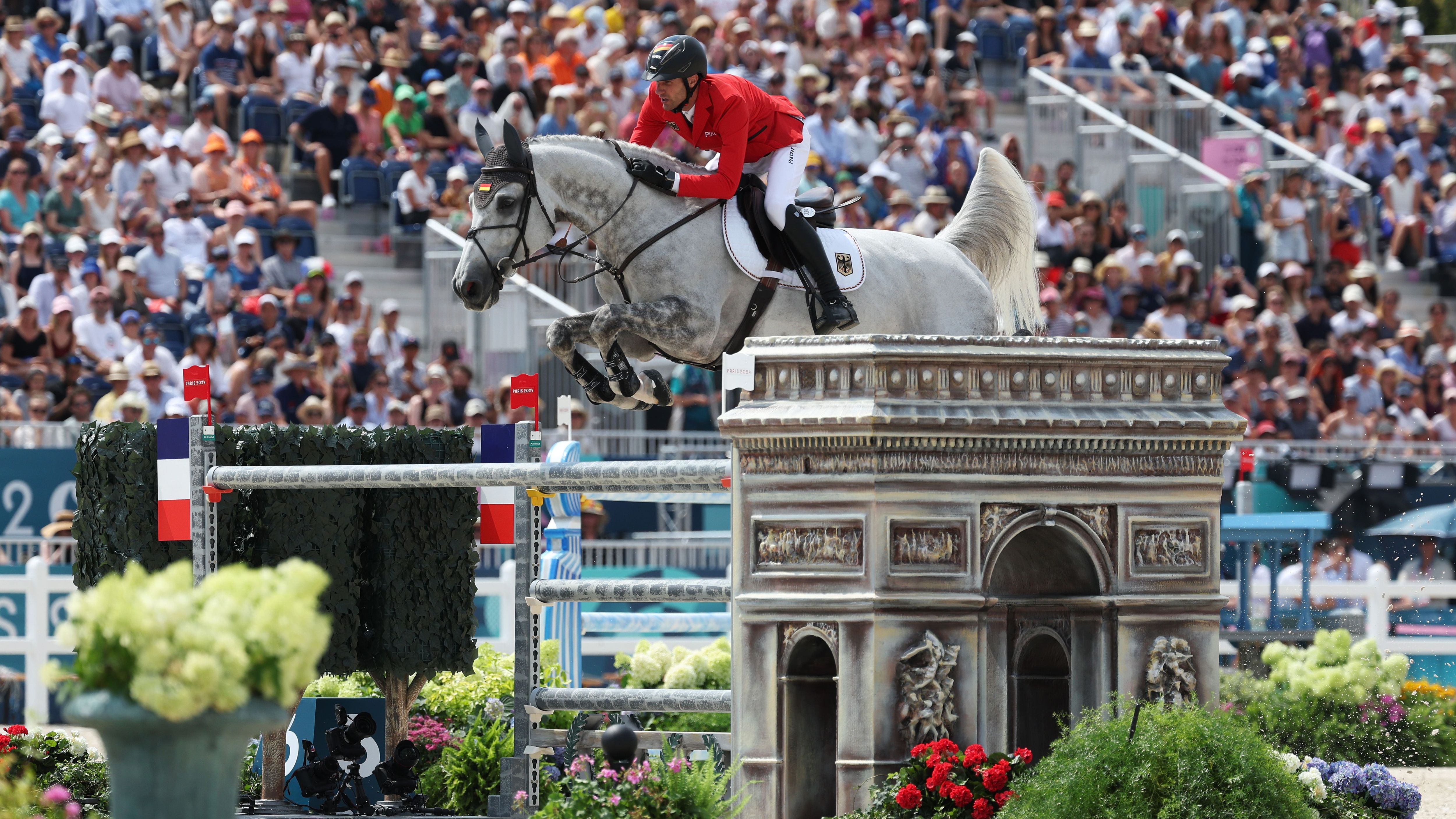 <strong>Olympia 2024: Die besten Bilder von Tag sieben</strong><br>Wenn die Springreiter sich auf ihre Pferde schwingen, steht der Arc de Triomphe auch mal in Versailles, wo der Wettbewerb ausgetragen wird.