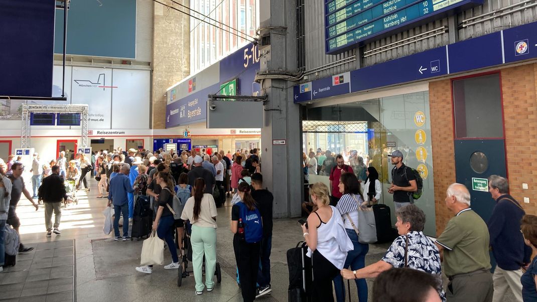 Reisende stehen am Reisezentrum der Bahn am Hauptbahnhof in München an.