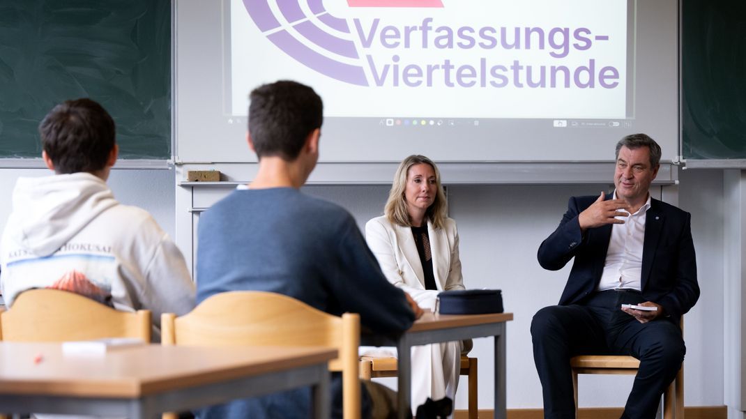 Markus Söder (CSU), Ministerpräsident von Bayern, und Anna Stolz (Freie Wähler), Kultusministerin von Bayern, nehmen am Wittelsbacher-Gymnasium in einer elften Klasse an einer Verfassungsviertelstunde teil.