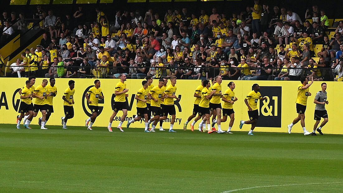 
                <strong>Der Trainingsauftakt von Borussia Dortmund</strong><br>
                Borussia Dortmund beginnt die Vorbereitung auf die neue Saison ohne die Neuzugänge Karim Adeyemi, Niklas Süle, Nils Schlotterbeck und Salih Özcan. Auch der verletzte Kapitän Marco Reus fehlt. Dennoch strömen etwa 1300 Fans zum Trainingszentrum in Dortmund Brackel.
              