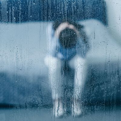 depressed woman sitting on bed and holding head in hands through