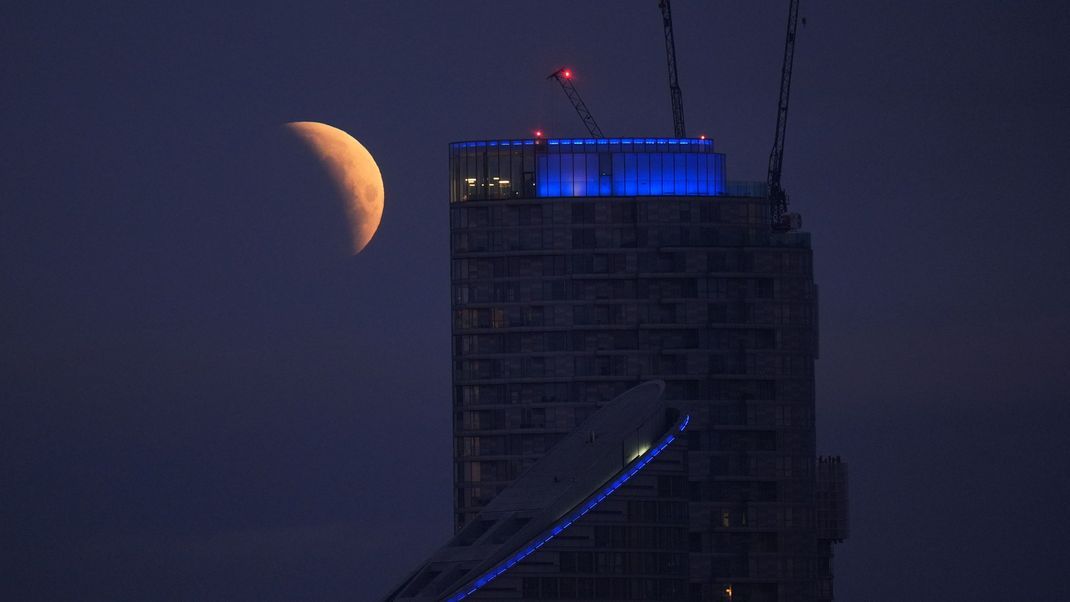 Großbritannien, London: Die Mondfinsternis ist über Canary Wharf zu sehen, als der Vollmond in den Erdschatten eintritt. 