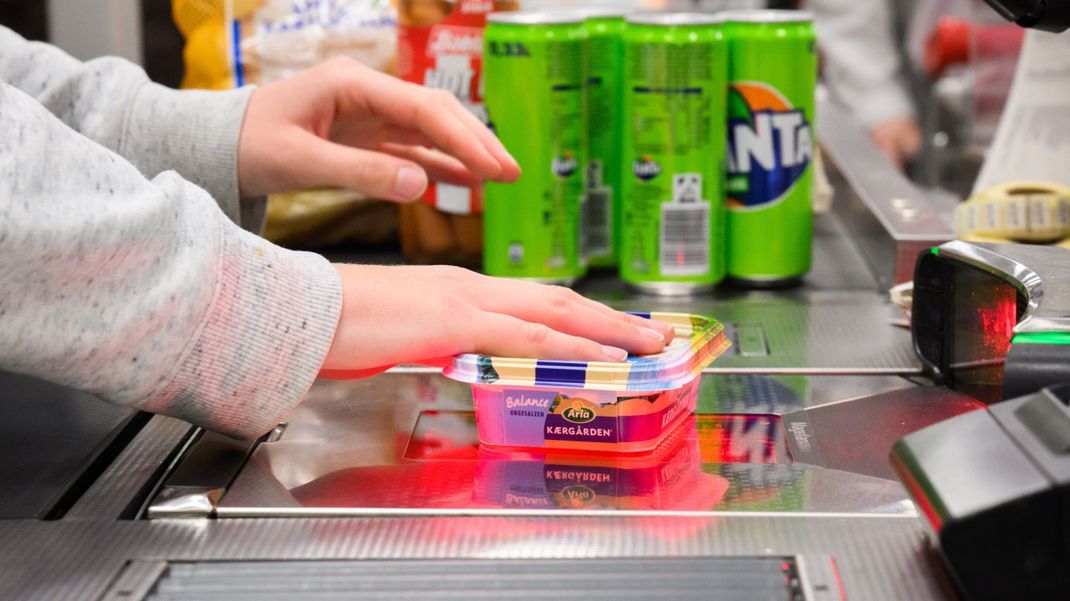 Eine Kassiererin scannt Butter an der Kasse eines Supermarktes. 