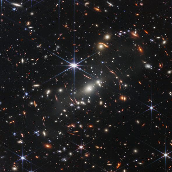 Das erste Bild zeigt das Galaxien-Cluster "SMACS 0723". Zum Vergleich: Der Ausschnitt des Universums auf diesem Foto entspricht etwa der Größe eines Sandkorns, das auf einer Armlänge Abstand gehalten wurde. 