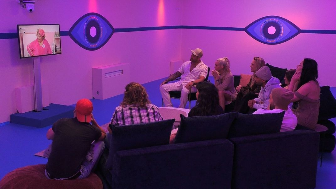 Big Brother 2024: Besuch von Cindy aus Marzahn im Container, die Bewohner:innen können die Comedienne live am Monitor verfolgen.