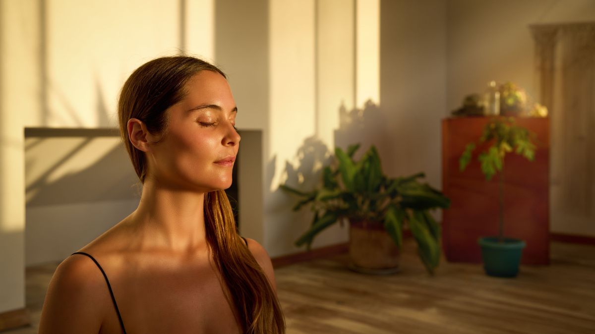 portrait young caucasian woman sitting with closed eyes meditating indoors