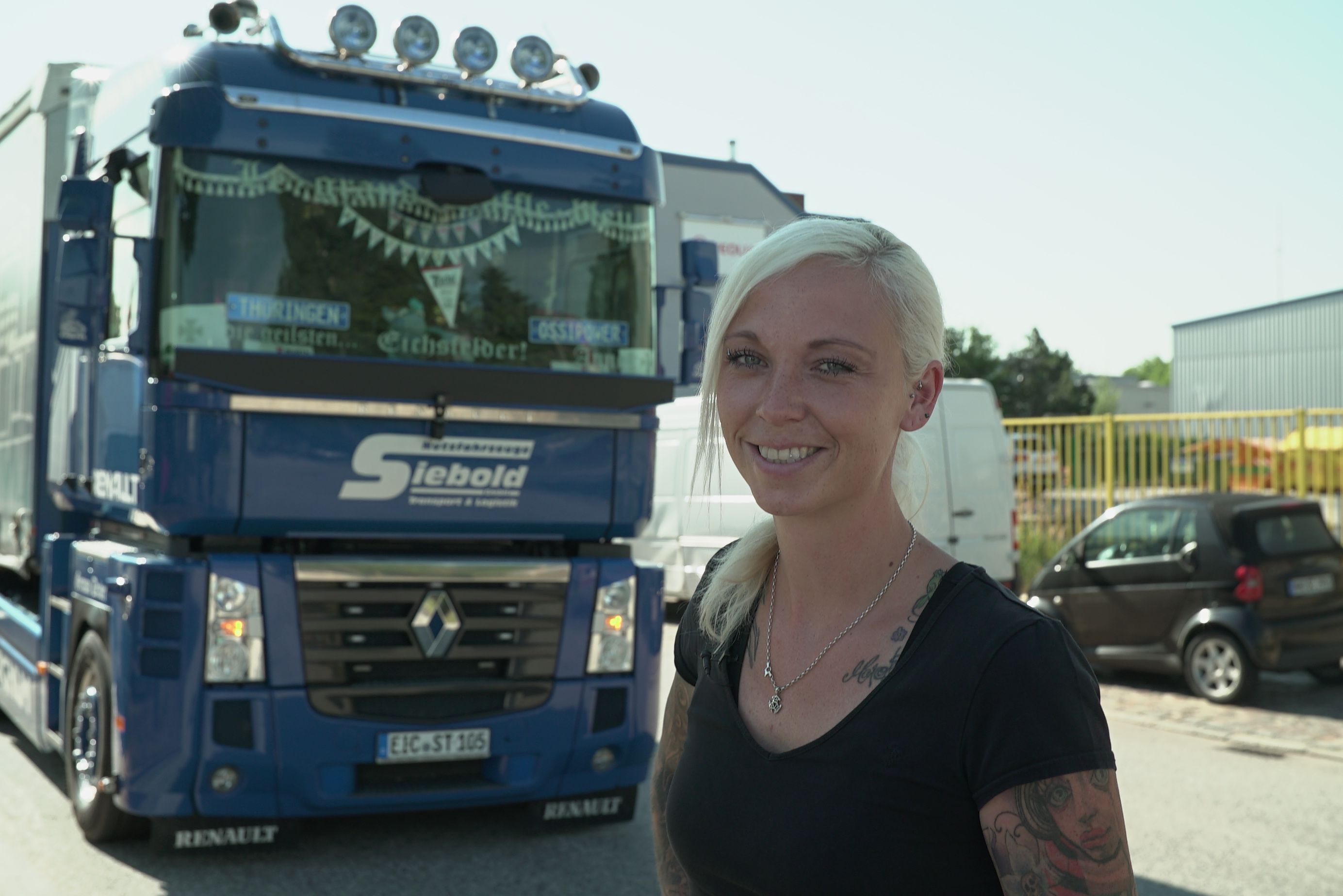 Während im Vordergrund des Fotos "Trucker Babe" Anne lächelt, steht im Hintergrund ihr Renault Magnum Truck.