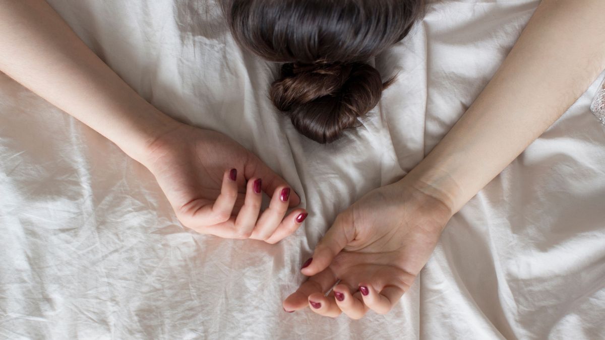 young woman lying in bed on white sheets