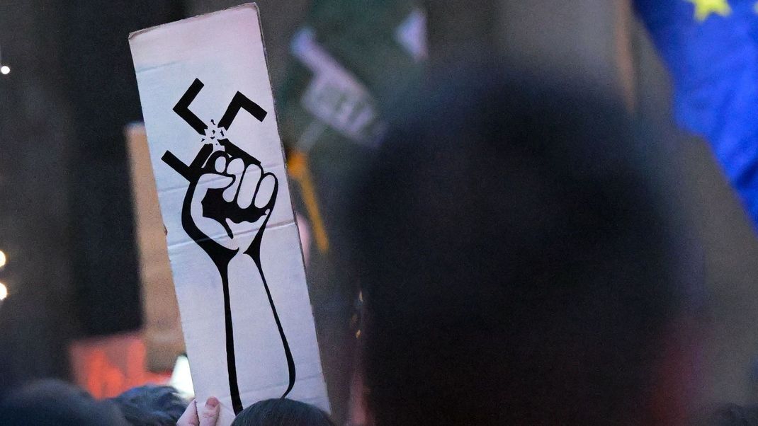 Menschen halten Schilder auf der Demonstration "Lichtermeer gegen den Rechtsruck" am Brandenburger Tor hoch.