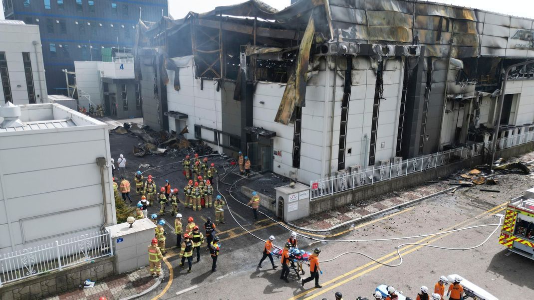 Feuerwehrleute transportieren eine Leiche am Ort des Brandes in einer Fabrik für Lithiumbatterien.