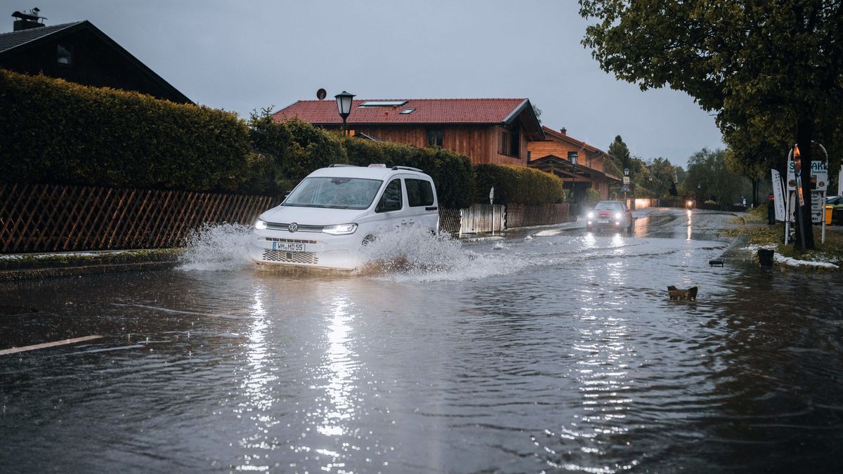 Nach starkem Regen fahren Autos durch Wasser, das in einer teils überschwemmten Straße steht.
