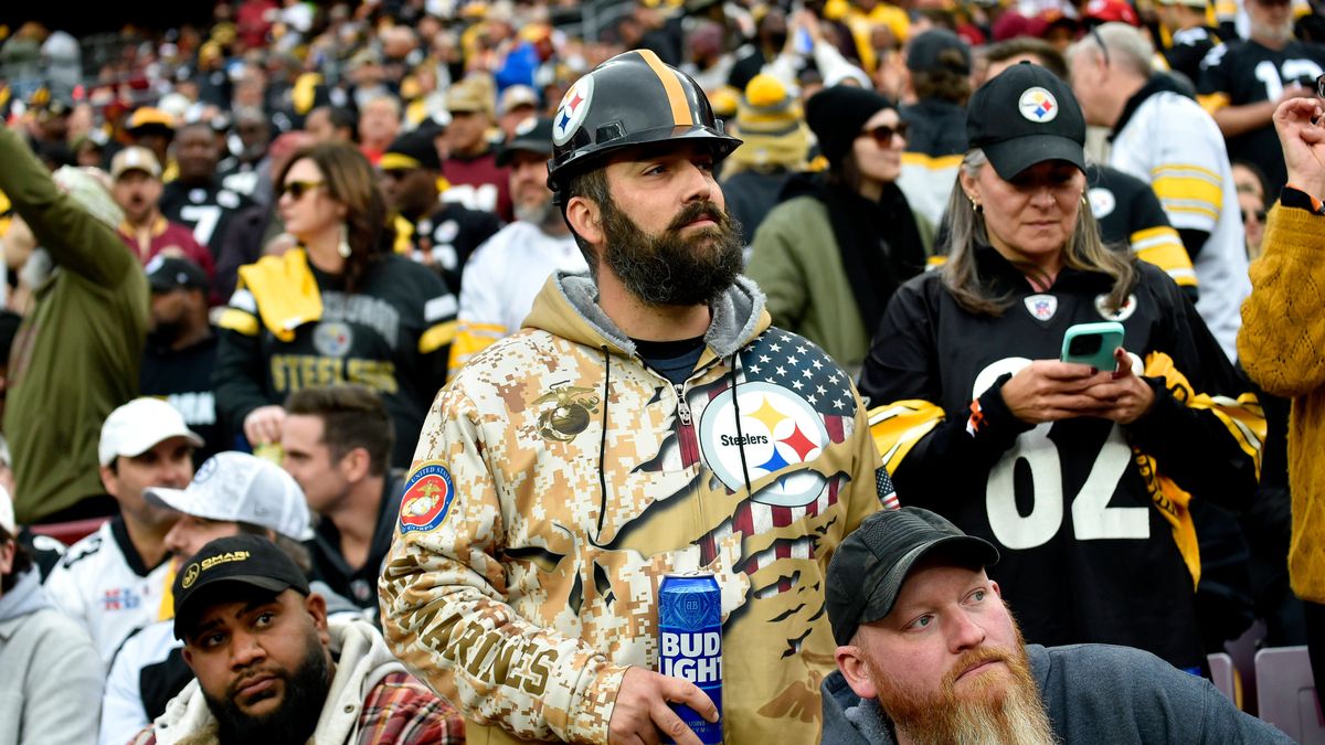 LANDOVER, MD - NOVEMBER 10: A Pittsburgh Steelers fan wearing a Steelers steel mill hard hat, a beard, a camouflage hoodie, and holding a Bud Light beer can watches during the Pittsburgh Steelers v...