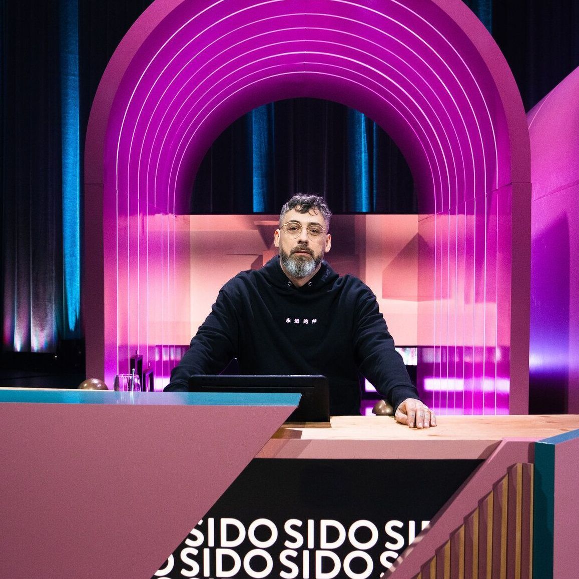 Sido sitzt an einem Ratepult im "Wer stiehlt mir die Show?"-Studio