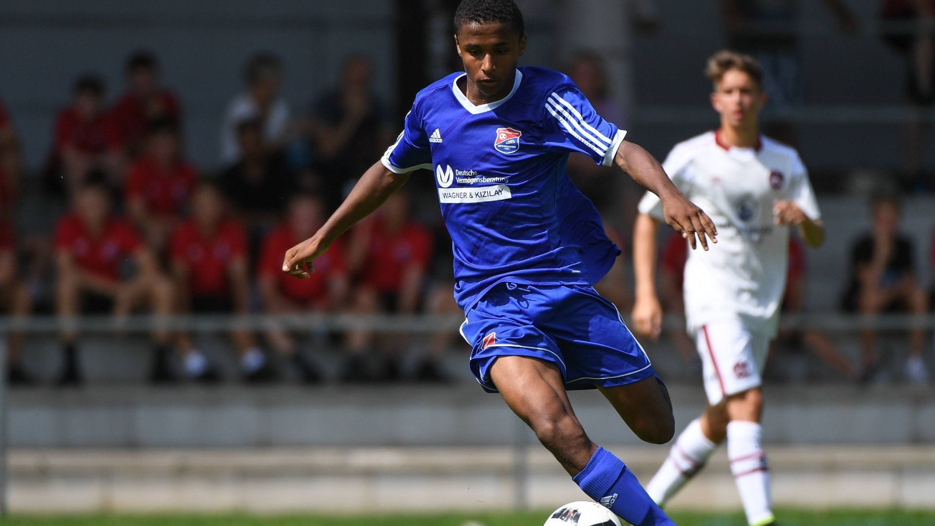 
                <strong>Karim Adeyemi</strong><br>
                Aus dem beschaulichen Unterhaching lockt Freund Karim Adeyemi im Sommer 2018 nach Salzburg. Kolportierte Ablösesumme für den damals 16-Jährigen: 3,3 Millionen Euro. Als der Nationalspieler 2022 zu Borussia Dortmund für geschätzte 30 Millionen Euro weiterverkauft wird, kassiert Haching dank des Verhandlungsgeschicks von Präsident Manfred Schwabl erneut – angeblich rund sechs Millionen Euro.
              