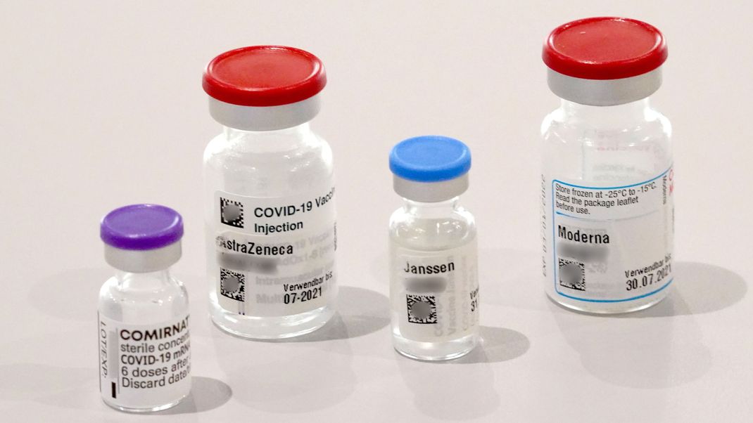 Behälter der Impfstoffe Biontech, Astrazeneca, Johnson & Johnson und Moderna stehen auf einem Tisch.