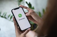 CHIANG MAI, THAILAND - JAN 16 2022 : Woman holding a iPhone and open appstore searching social Internet service WhatsApp on the screen. iPhone was created and developed by the Apple inc