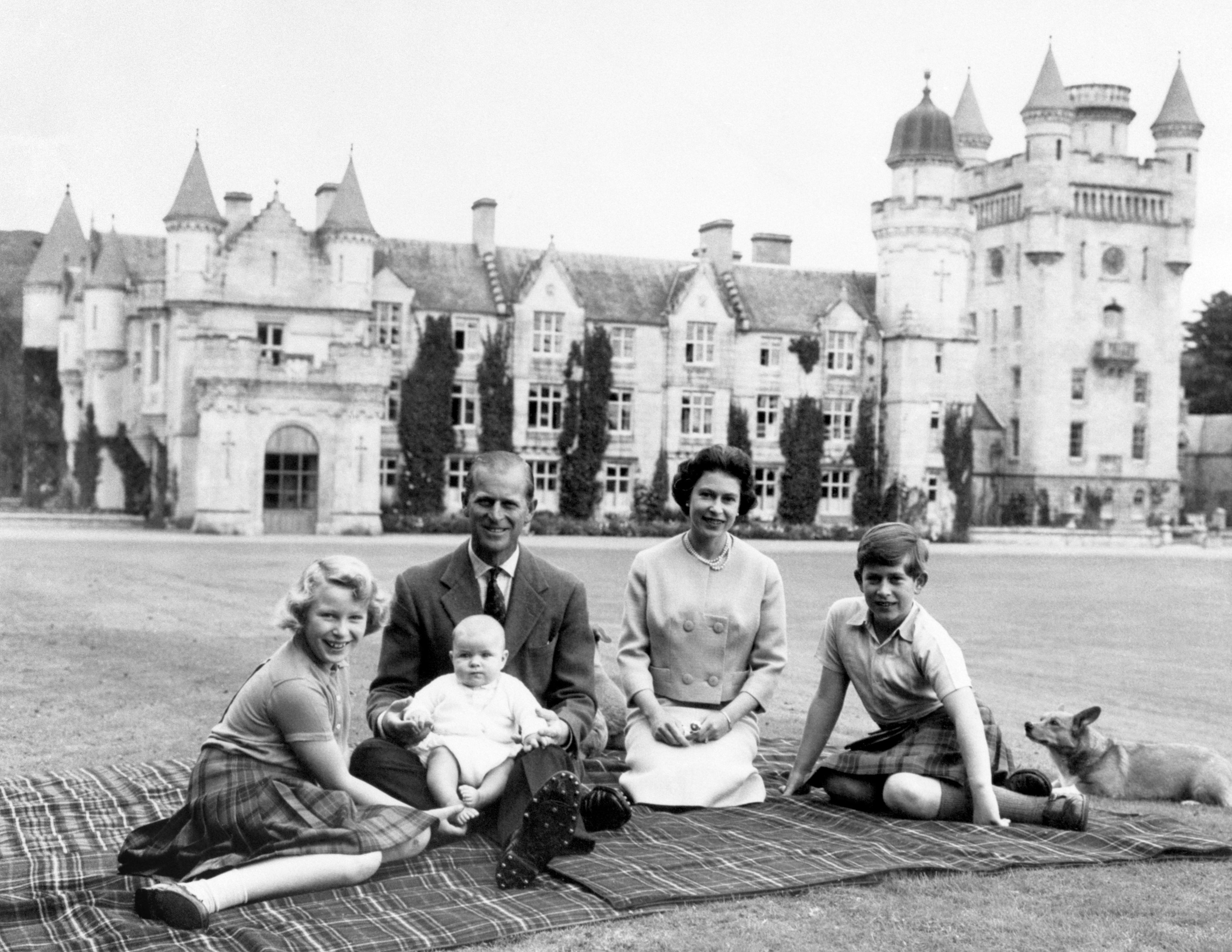 The Duke of Edinburgh and three of their children Princess Anne, Prince Charles and baby Prince Andrew, on his father's knees on the lawns at Balmoral.