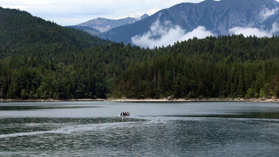 Polizeitaucher fahren in einem Schlauchboot über den Eibsee. 